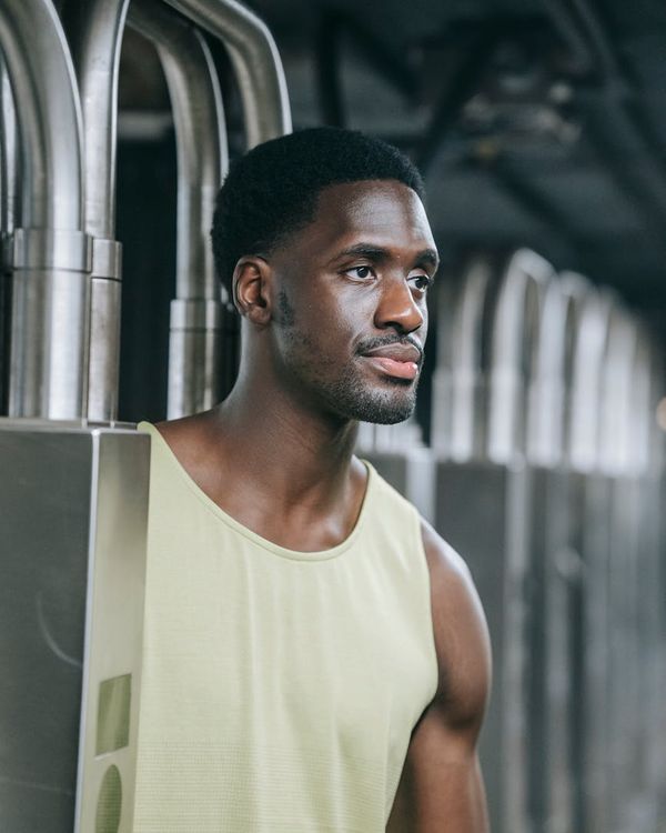 Man in a focused athletic stance in a dark, modern gym.